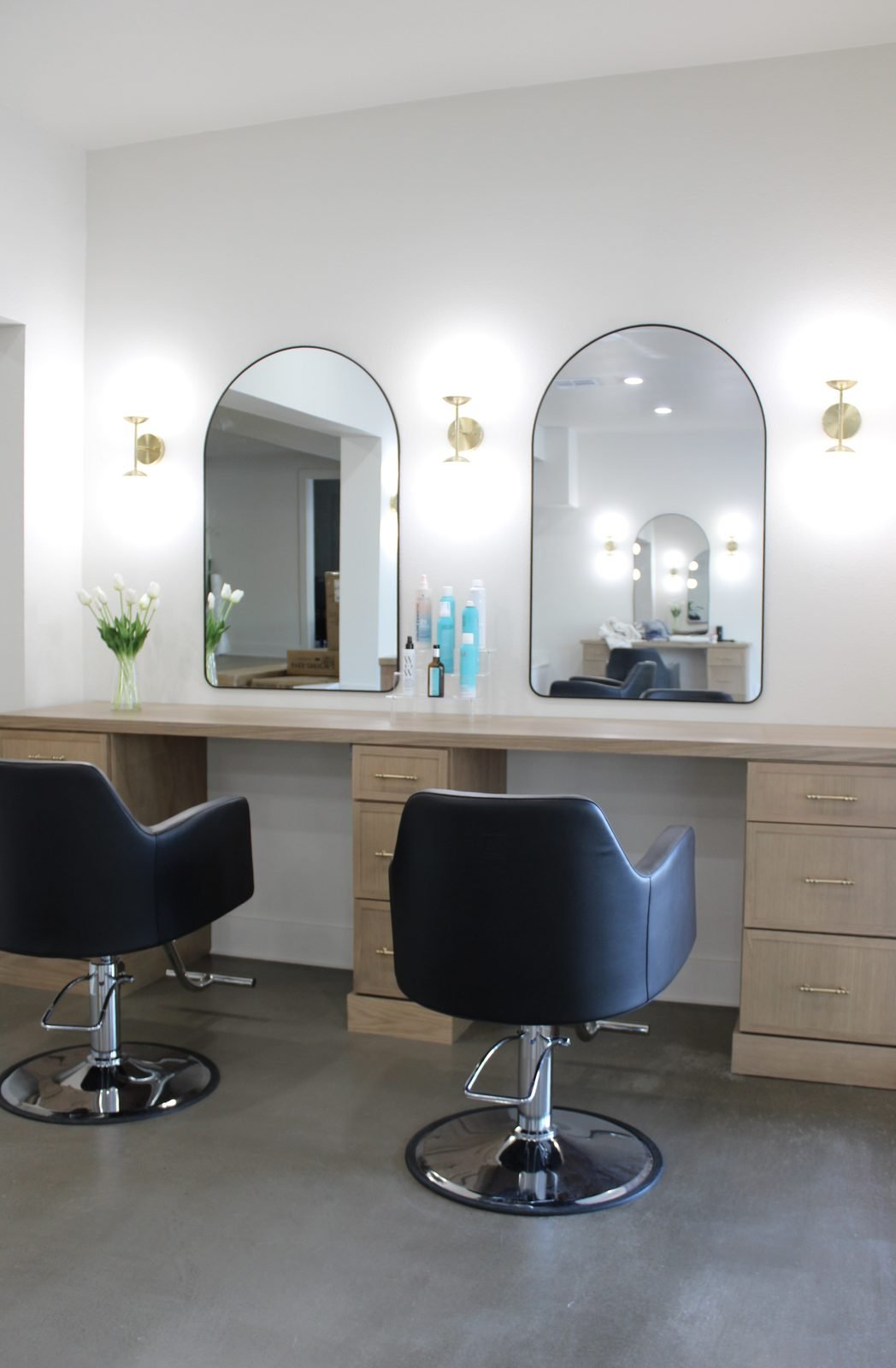 Commercial salon build-out in Winter Haven, FL with custom oak vanity, arched mirrors, and brass sconces